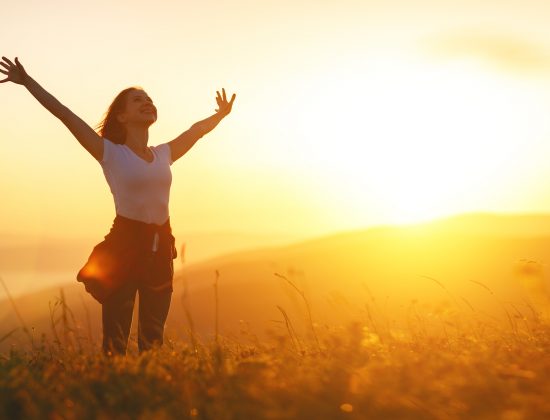 Happy woman   on the sunset in nature in summer with open hands